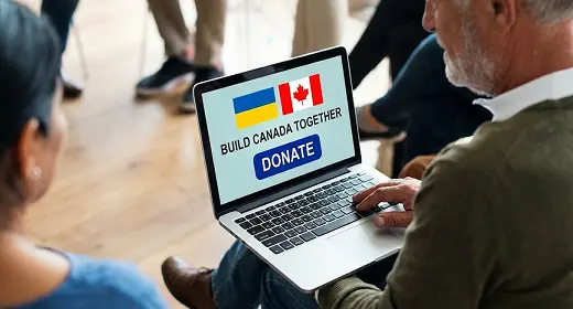 Man holding a laptop with screen showing Ukrainian and Canadian flags and a 'Build Canada Together' message with a blue DONATE button.