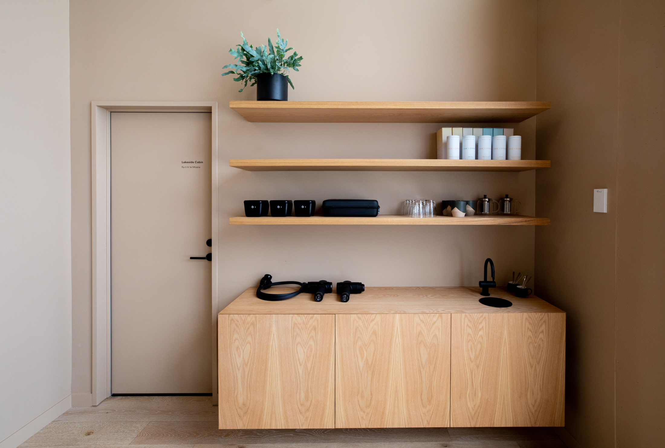 A tranquil O-Studio recovery room with minimalist wooden shelving, cabinet, and sink area, designed for post-session relaxation and rejuvenation.