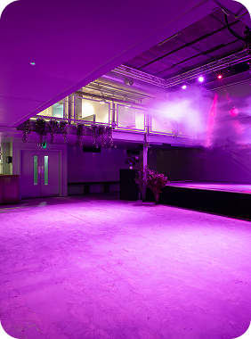 Empty stage and seating area illuminated with purple lighting and fog in a modern event venue.