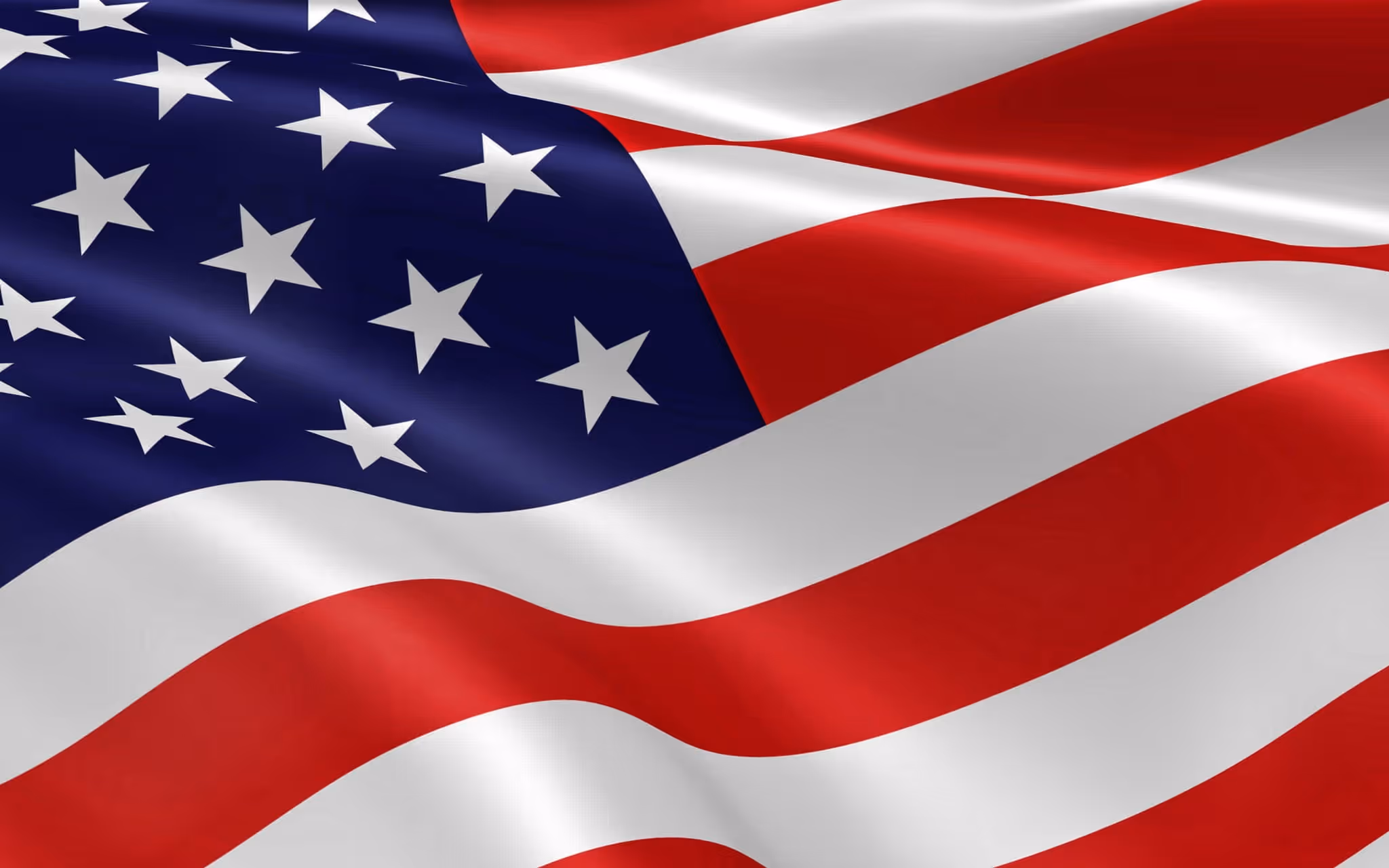 Close-up of the waving flag of the United States showing white stars on a blue field and red and white stripes.