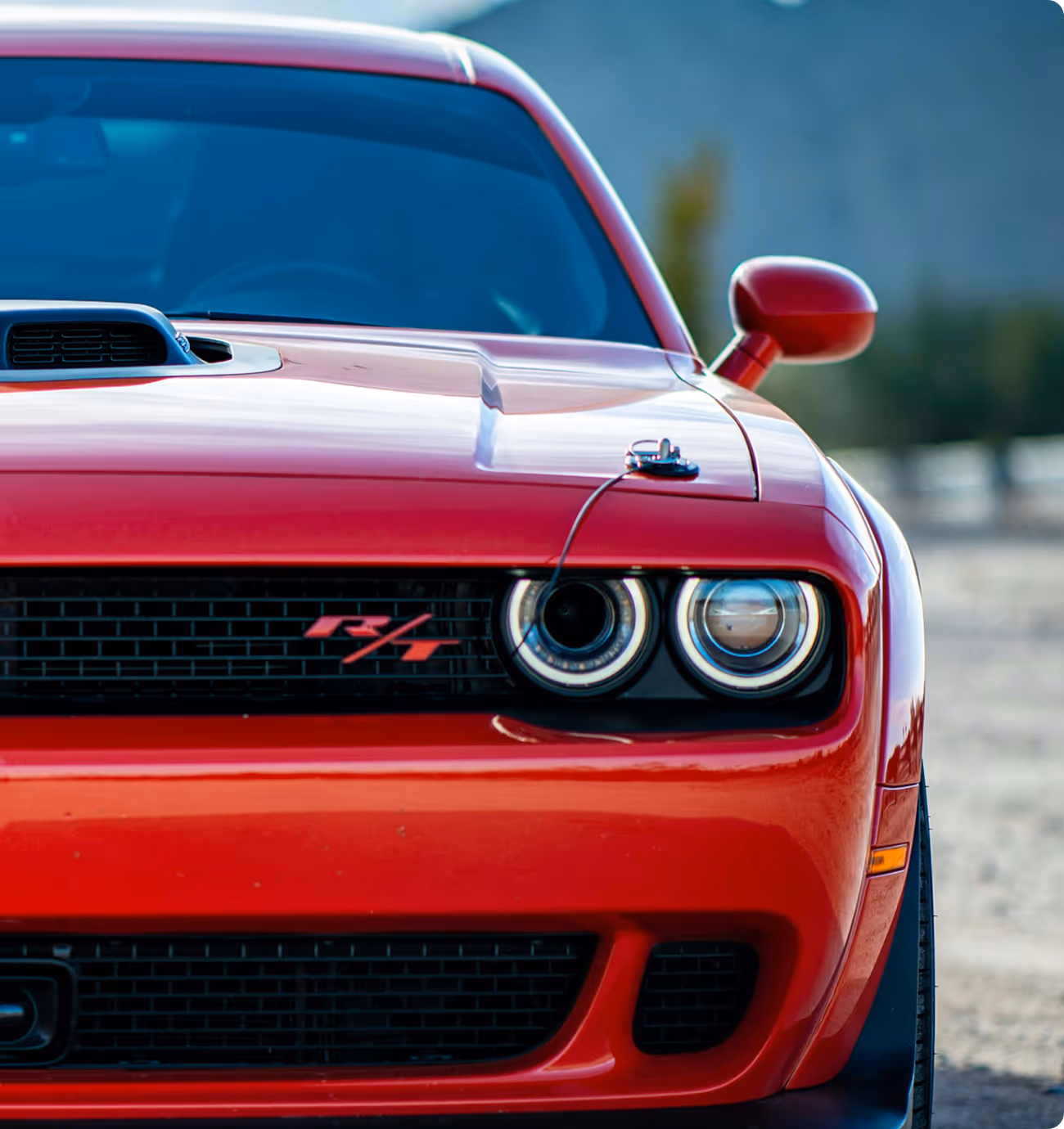 Widok z przodu czerwonego Dodge’a Challengera R/T z podwójnymi okrągłymi reflektorami i wlotem powietrza na masce. Ikona amerykańskiej motoryzacji