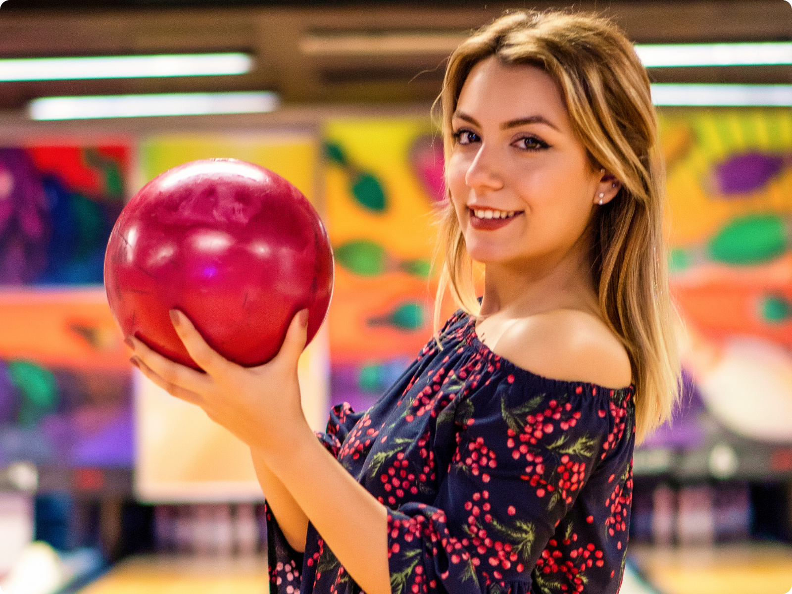 Female hotel receptionist wearing a name tag reading 'Tijana Trainee' working at the front desk with a male colleague on the phone in the background.