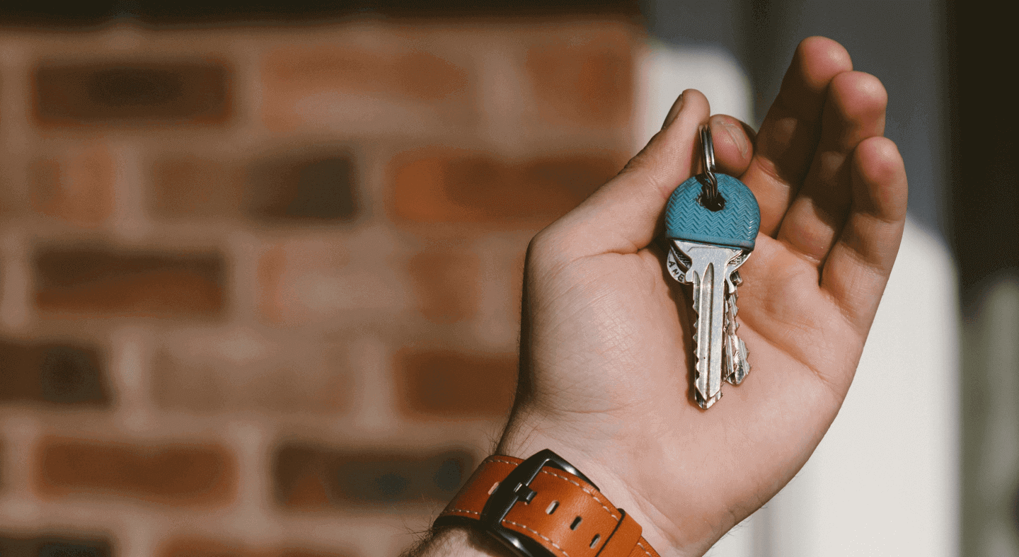 Close-up of a person's hand holding house keys, indicate a new home or a real estate transaction.