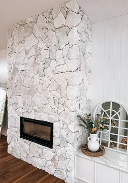 Luxury stone fireplace feature wall installed in a custom residential interior.