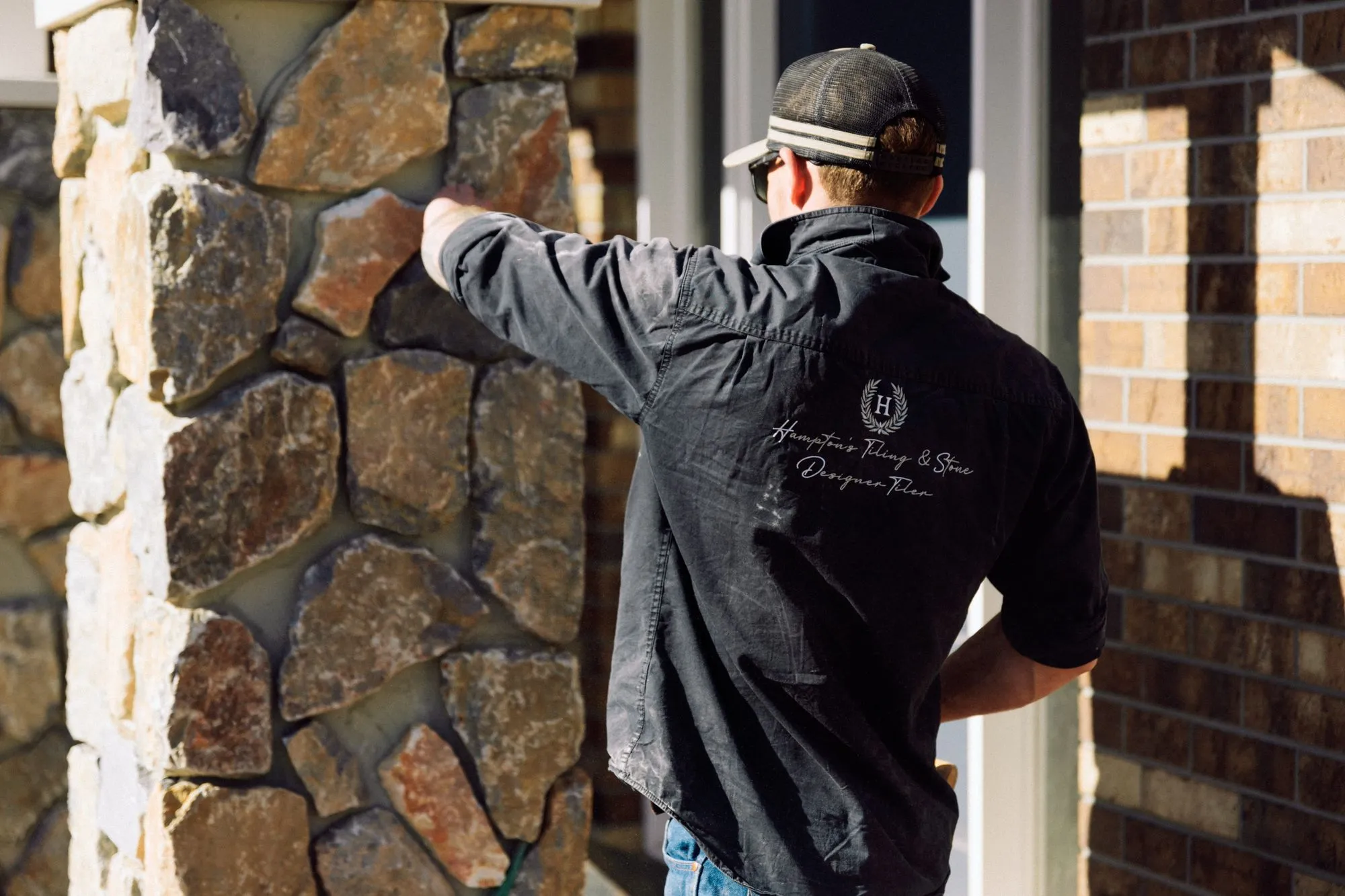 Skilled stone mason installing natural stone cladding for a high-end residential project in Toowoomba.