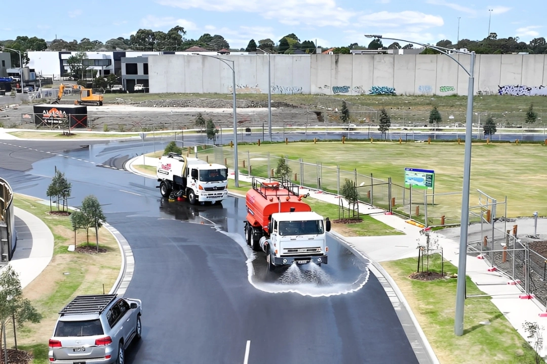 Man and woman wearing gloves carrying gardening tools and branches while walking outdoors.