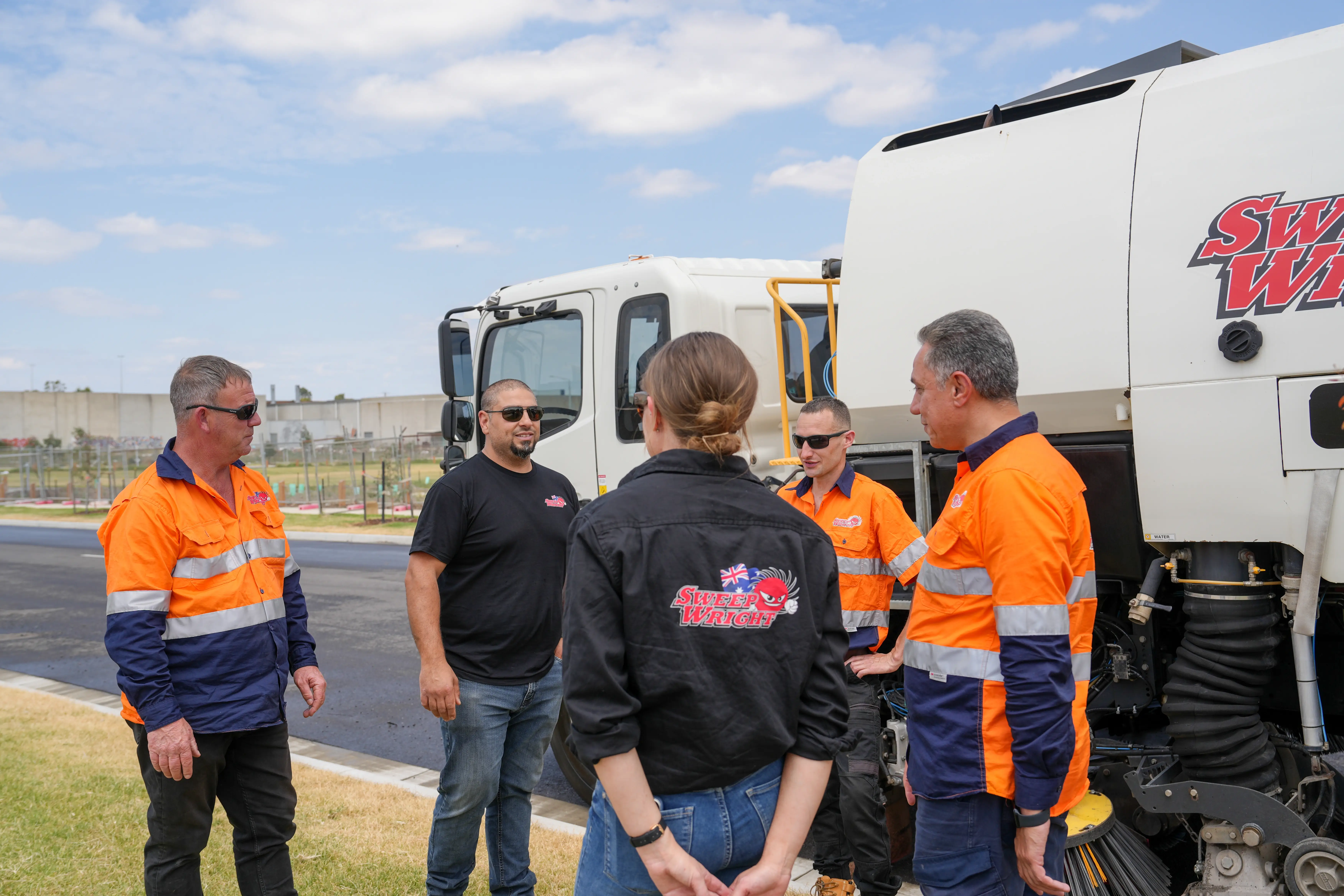 Man and woman wearing gloves cleaning up trash outdoors in a wooded area.