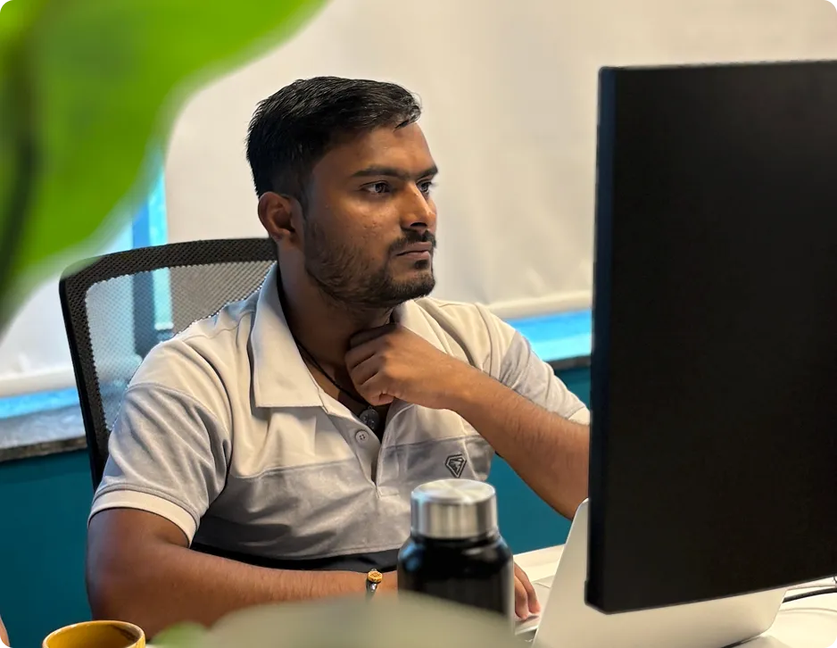 Man with short hair and beard sitting at a desk, looking intently at a computer monitor.