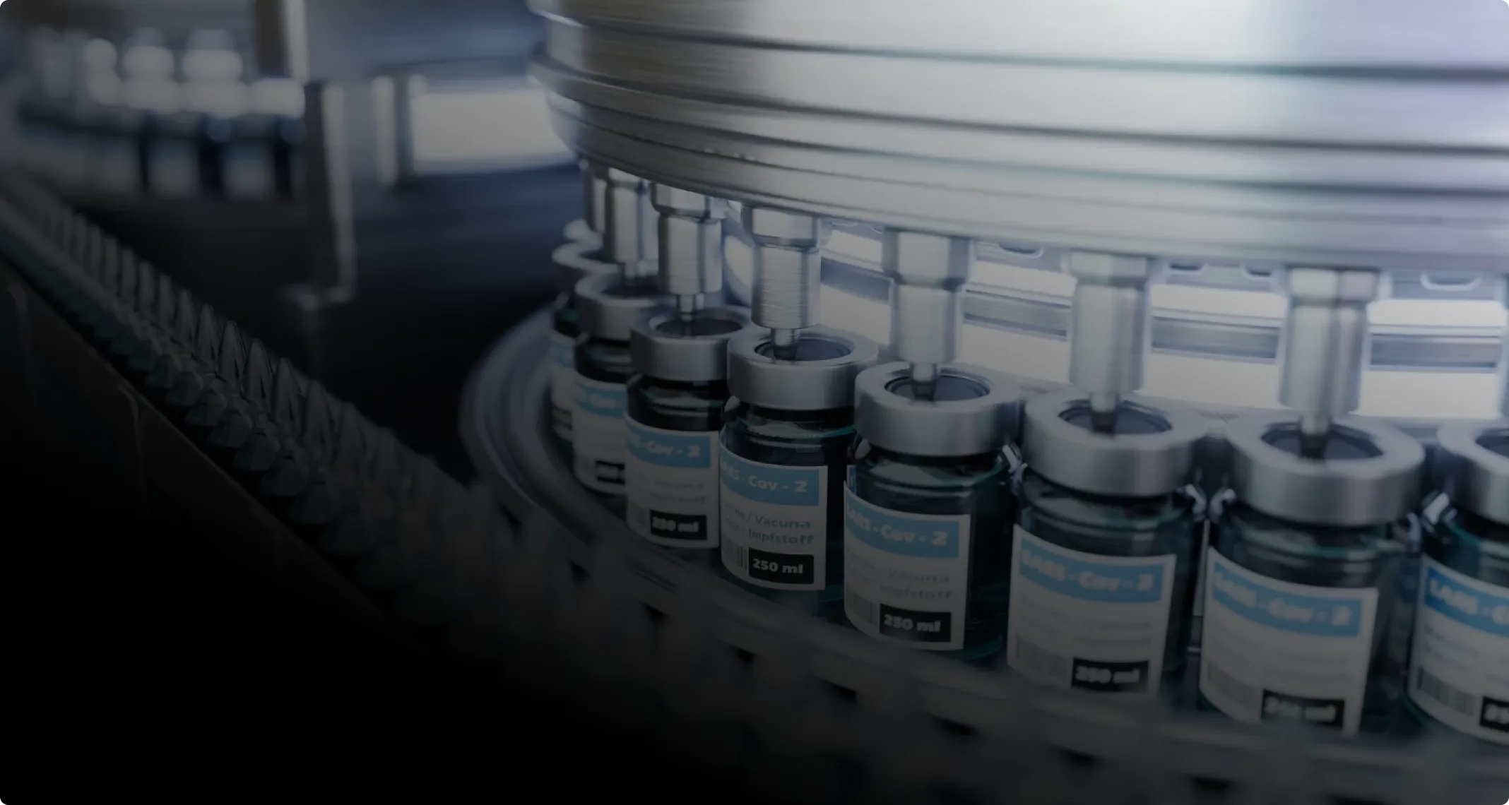 Automated filling machine inserting liquid into multiple COVID-19 vaccine vials on a production line.