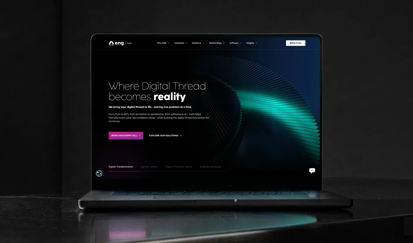 A sleek laptop mockup on a dark, reflective surface displaying the desktop homepage of the IndX website, designed by Pavero