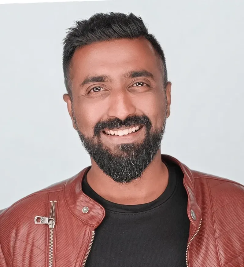 Smiling man with short black hair, beard, wearing a brown leather jacket and black shirt.
