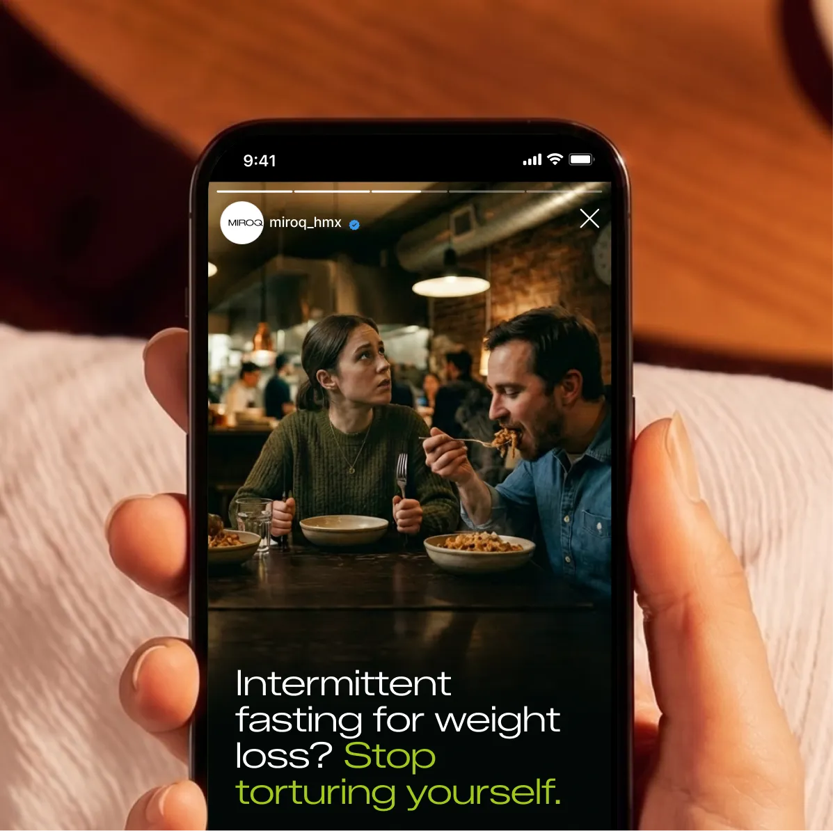 Smartphone showing a man eating pasta and woman waiting with empty plate, text about intermittent fasting.