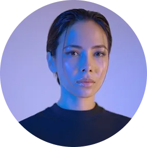 Portrait of a woman with wet hair and blue lighting on a purple background.