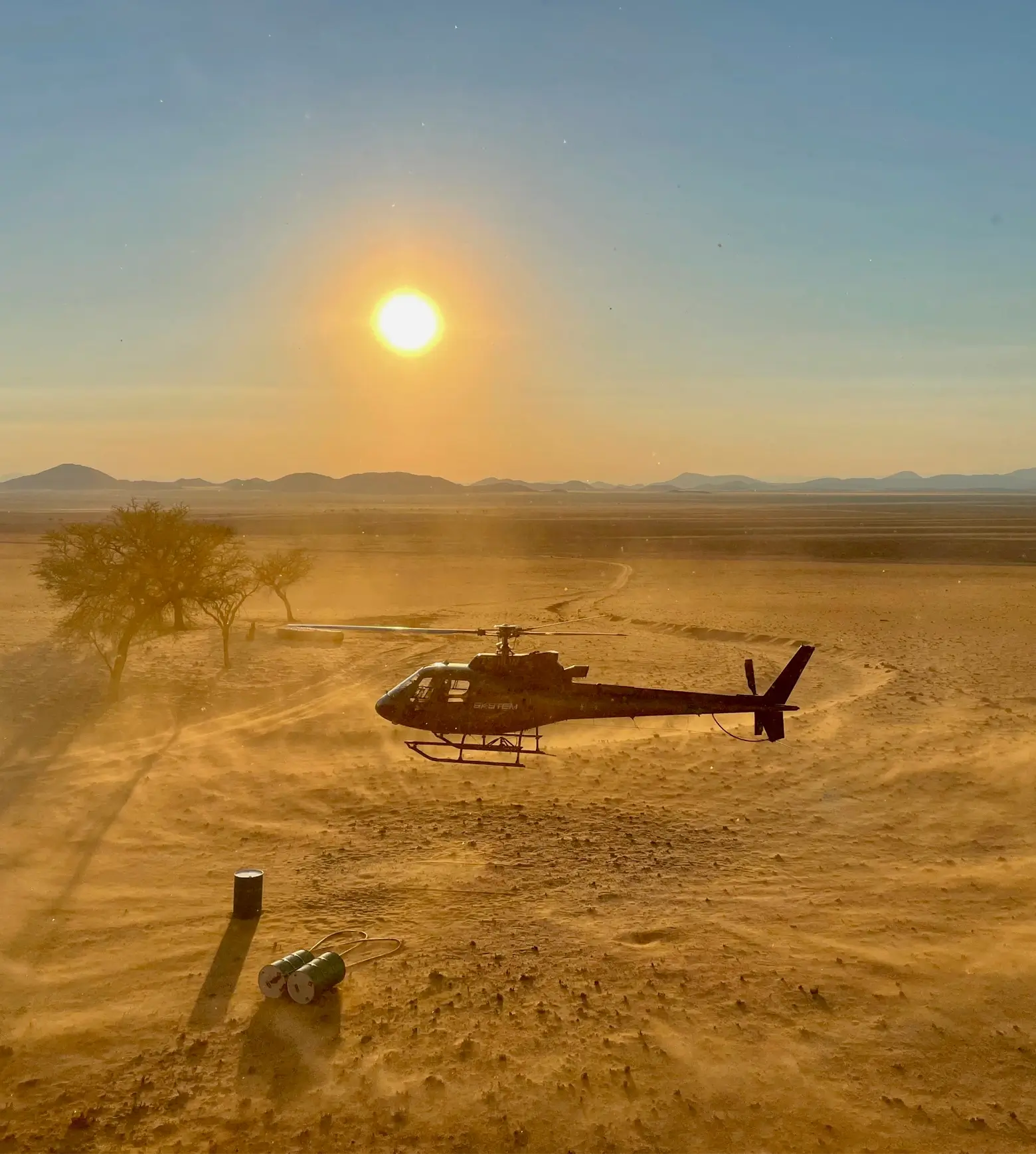 Helicopter landing in the desert at sunset during a SkyTEM survey