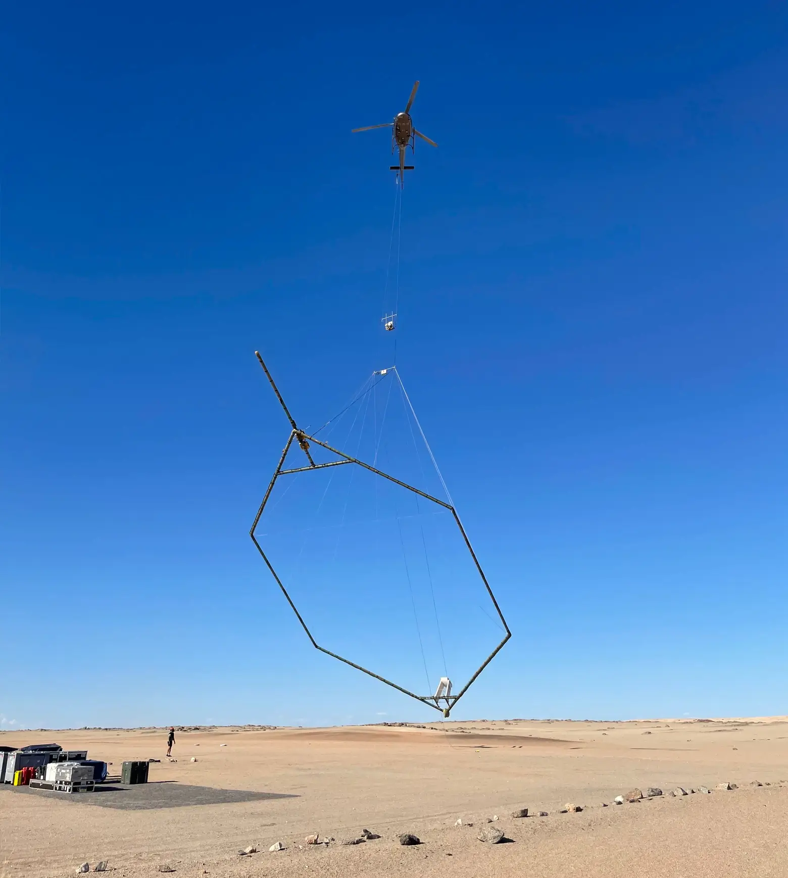 Helicopter lifting a SkyTEM transmitter loop over the desert