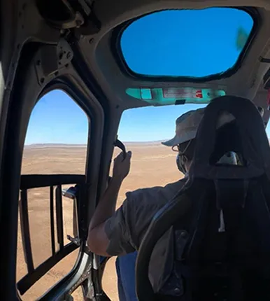 View from a helicopter cockpit over arid terrain during a survey flight