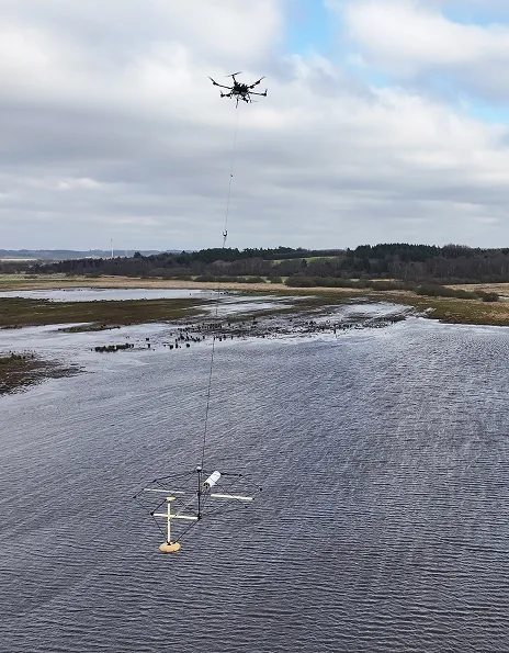 Drone carrying an electromagnetic sensor over wetland