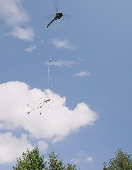 Helicopter carrying a SkyTEM sensor frame under a blue sky