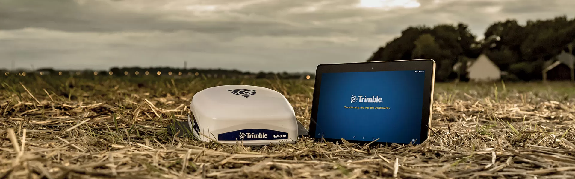 Поле с устройство Trimble NAV-900 и таблет с показан лого Trimble на екрана.