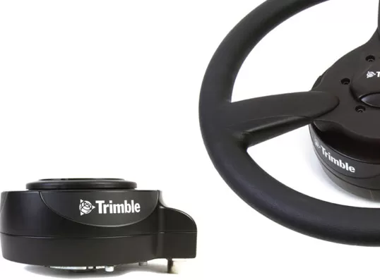 Водач управлява трактор с волан Trimble.