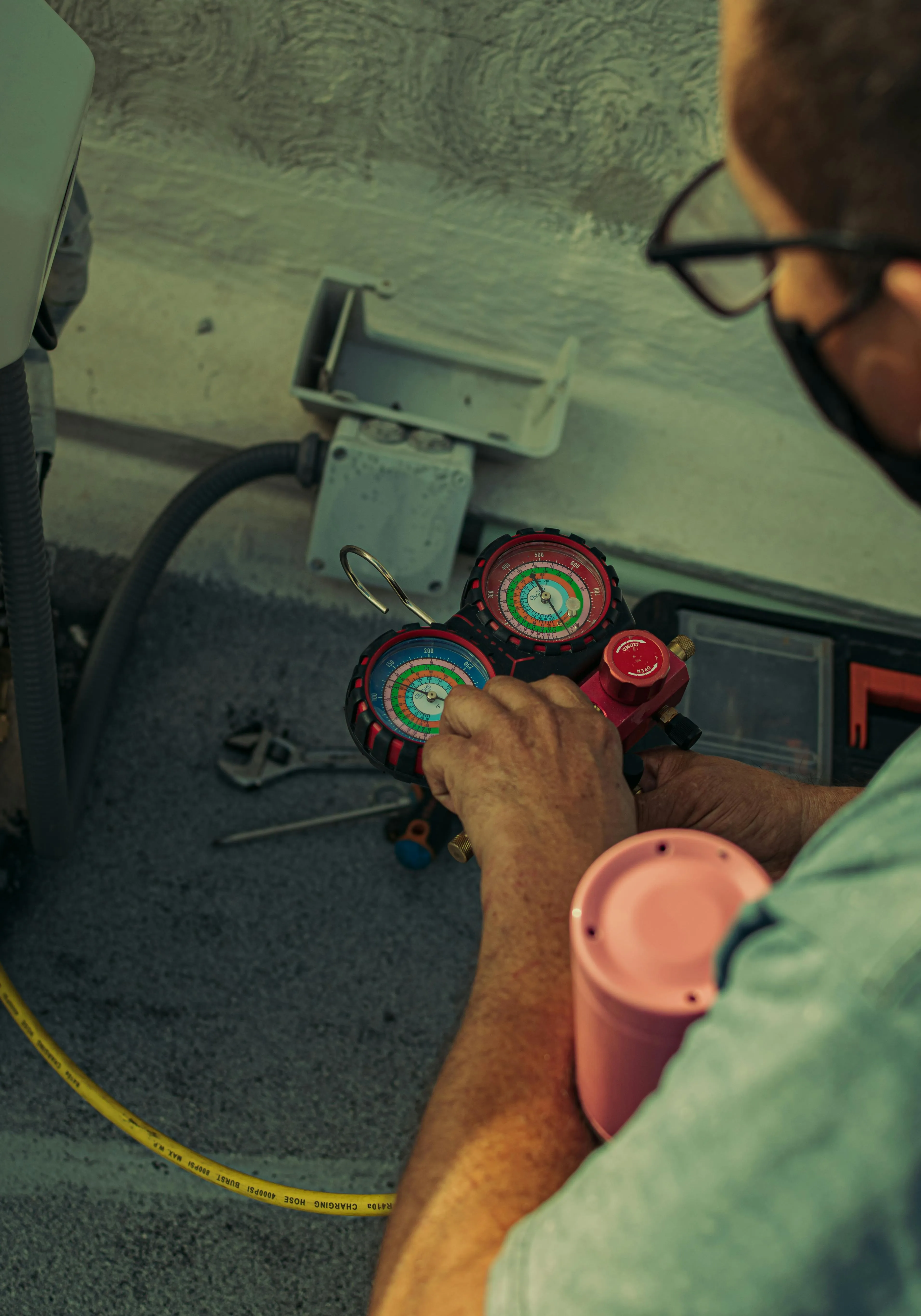 Technicien analysant les pressions du circuit frigorifique d'une climatisation avec un manomètre bi-branche