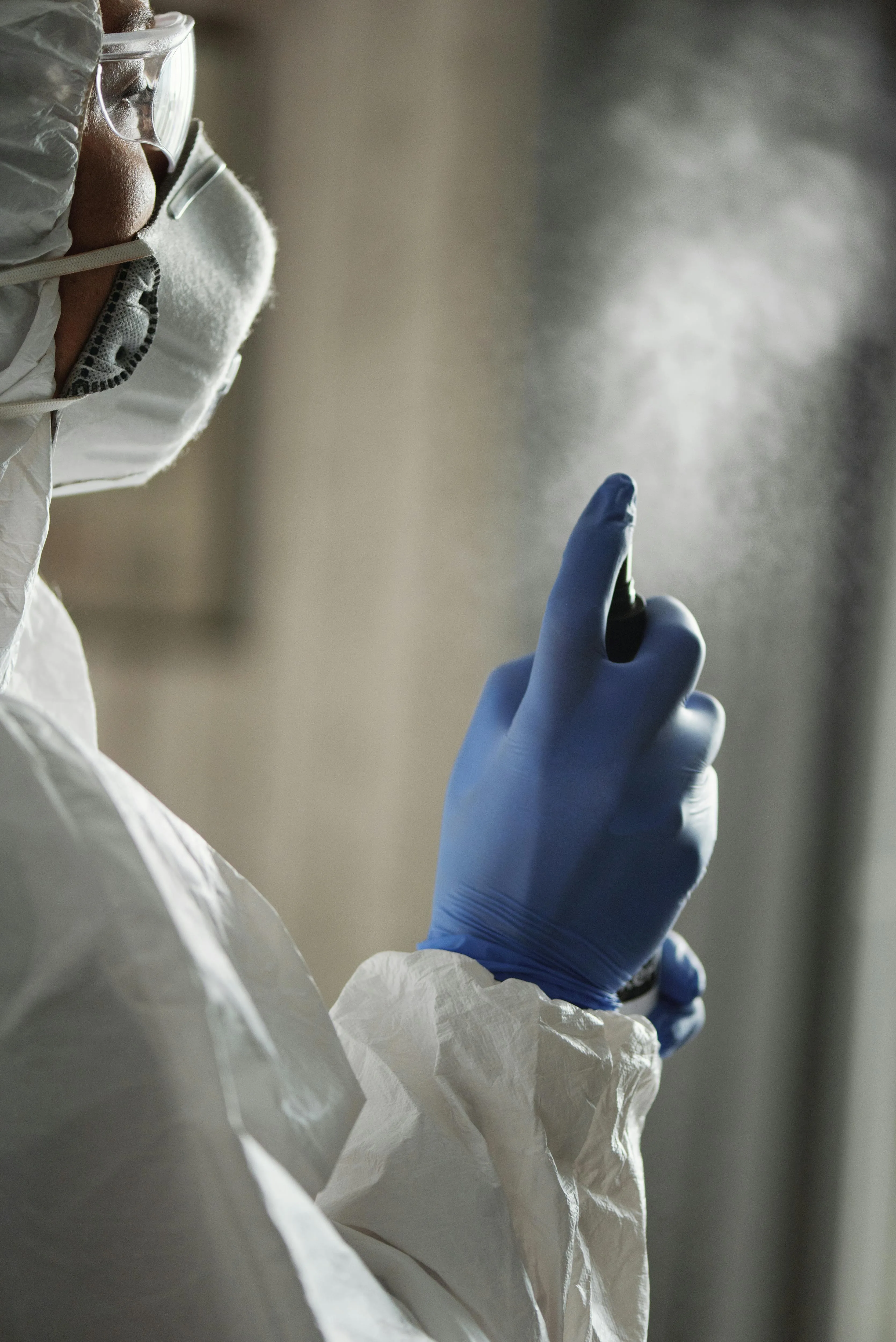 Technicien en combinaison de protection effectuant la désinfection antibactérienne d'une climatisation