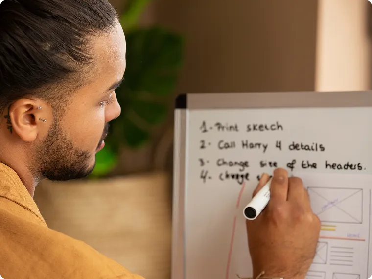 Man writing tasks on a whiteboard, including 'Print sketch' and 'Call Harry 4 details'.