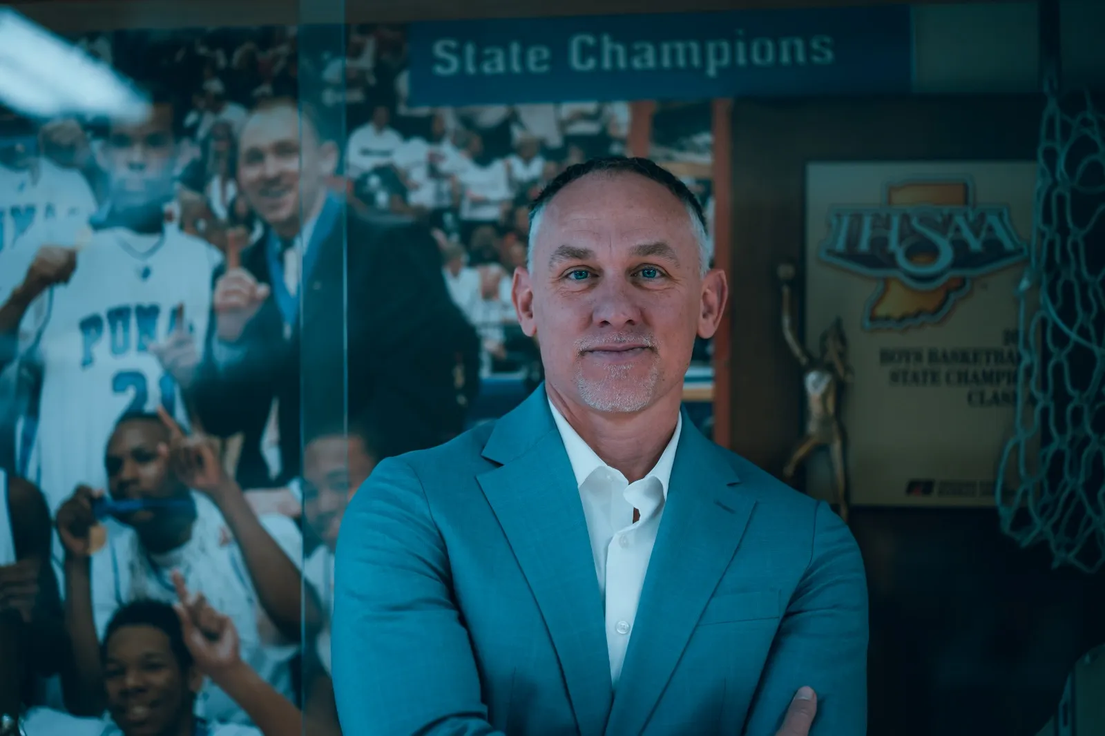 A man in a blue suit standing in front of a wall.