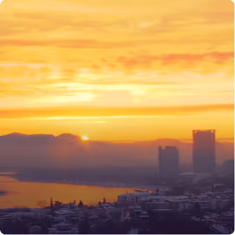 Sonnenaufgang über einer Stadt mit Fluss und Bergen im Hintergrund, mit gelbem Himmel.