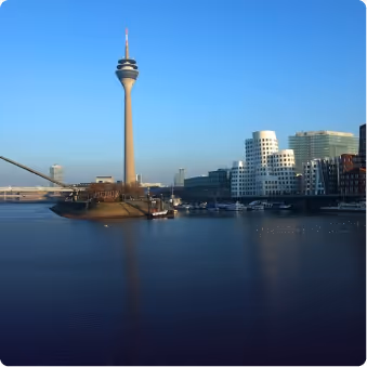 Blick auf den Rheinturm und moderne Gebäude in Düsseldorf am Rhein bei klarem Himmel.