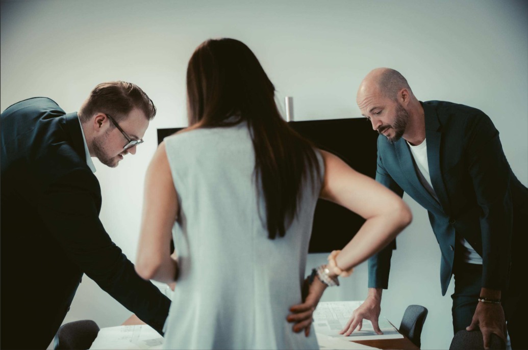 Team von Puentes Real Estate im gemeinsamen Austausch über einen Lageplan – Strategische Beratung.