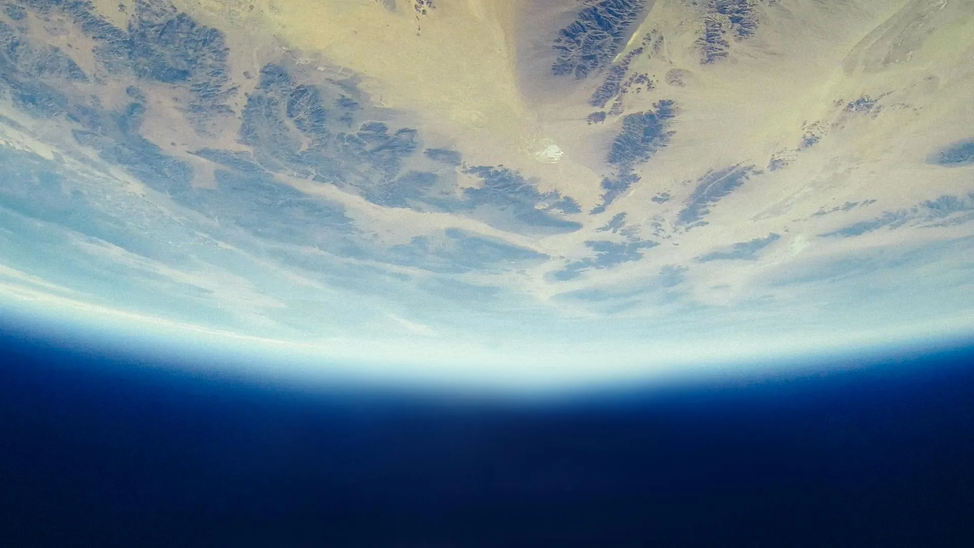 View of Earth from space showing desert terrain and the planet’s curved horizon.