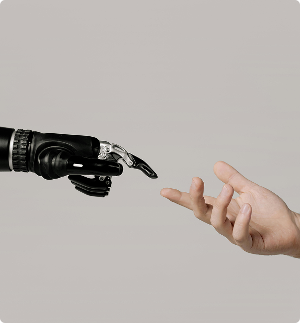 Human hand reaching out to touch a robot hand against a neutral gray background.