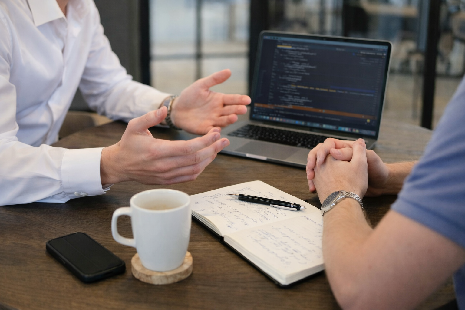 Twee mensen aan tafel die aan het overleggen zijn