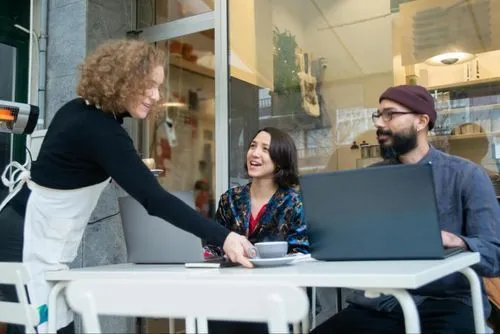 A waitress serving coffee to two smiling customers