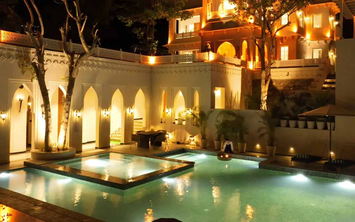 Warmly lit arched courtyard and swimming pool at YAMA Villa at night