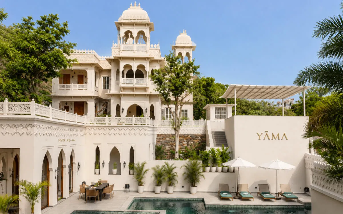 YAMA Villa courtyard pool with lounge chairs and umbrellas in front of the main building