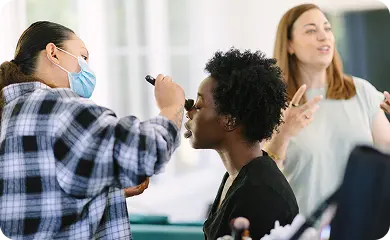 Makeup artist preparing talent on set before a video shoot