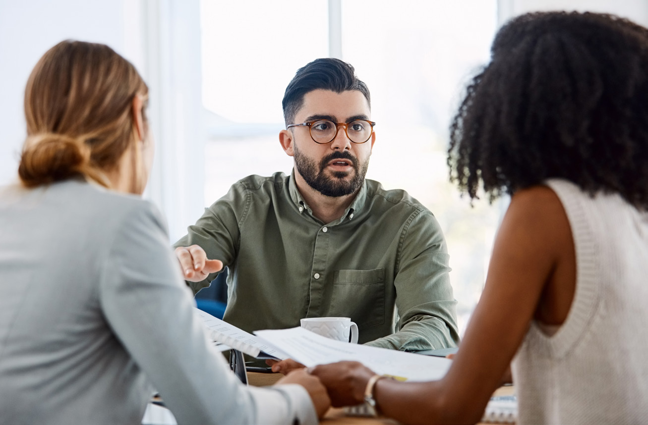A nonprofit team gathered around a table working through software requirements together.