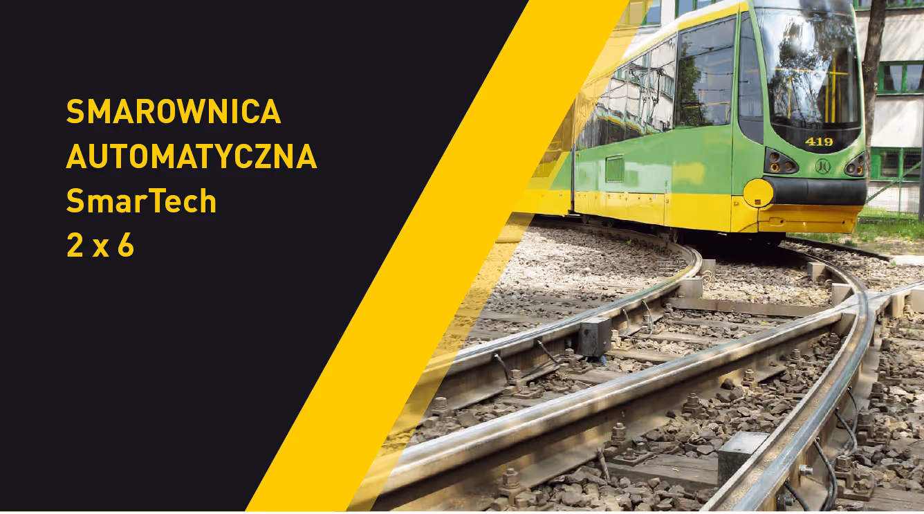 Zielono-żółty tramwaj na torach kolejowych obok tekstu reklamującego automatyczną smarownicę SmarTech 2 x 6.