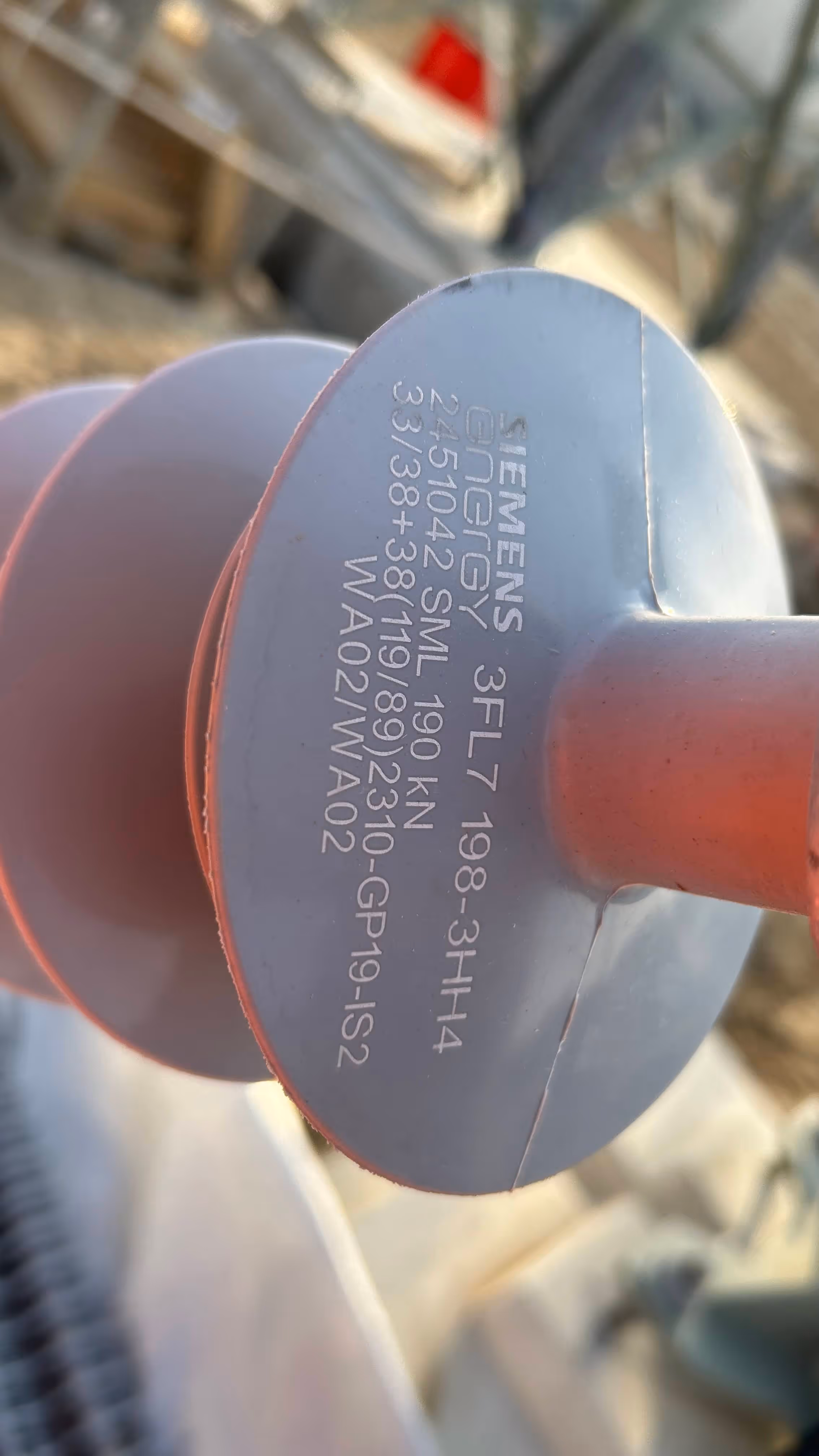 Czerwono-szary izolator energetyczny Siemens z nadrukowanymi specyfikacjami technicznymi.