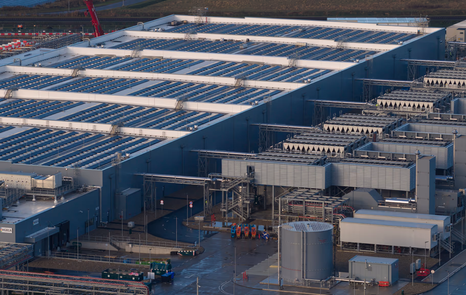 Large industrial facility with rows of solar panels on the roof and extensive cooling and mechanical structures.