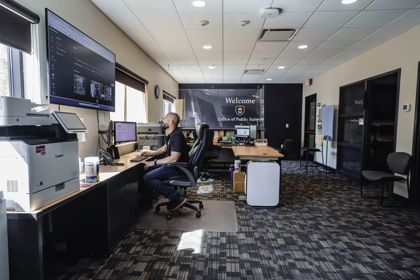 University of Northwestern security officer monitoring live Ambient.ai alerts on a wall-mounted display in the Office of Public Safety