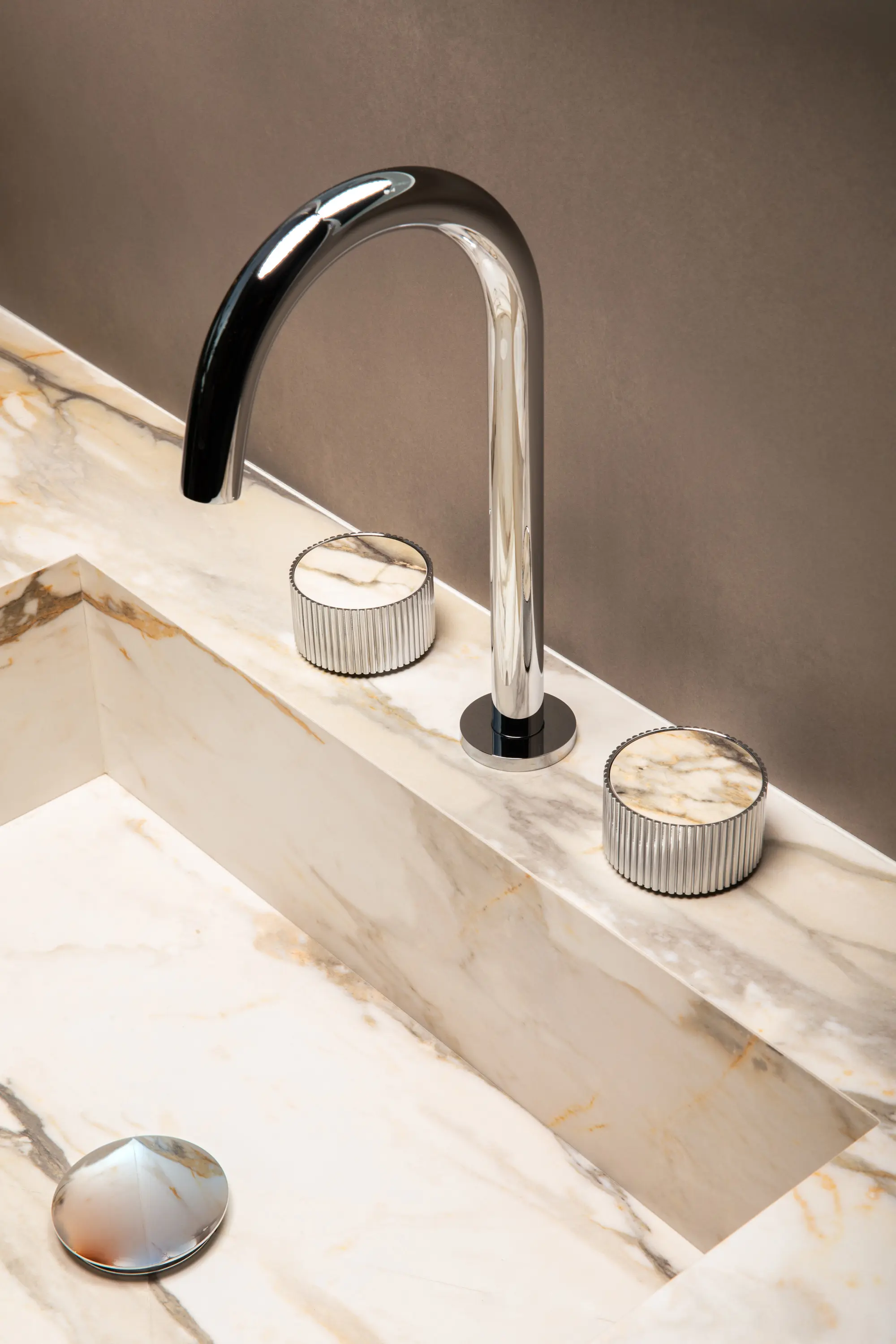 Modern bathroom sink with a marble countertop and a sleek chrome faucet with two matching round handles.