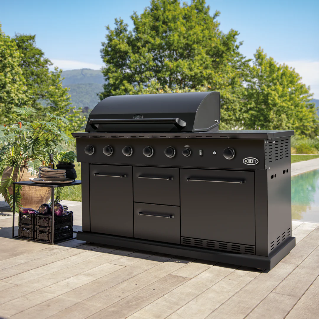 Black Boretti outdoor gas grill with multiple knobs and storage compartments on a wooden deck by a pool and garden.