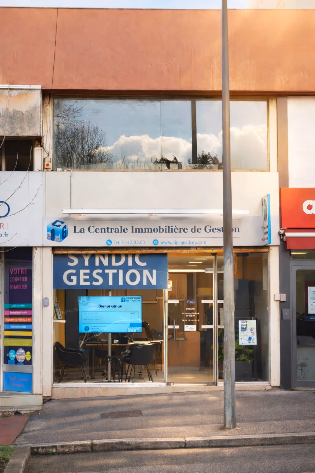 Façade d'une agence immobilière avec une vitrine en verre et un panneau indiquant La Centrale Immobilière de Gestion.