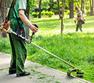 Mitarbeiter bei der Grünflächenpflege mit Freischneider – Rasen- und Randpflege in NRW