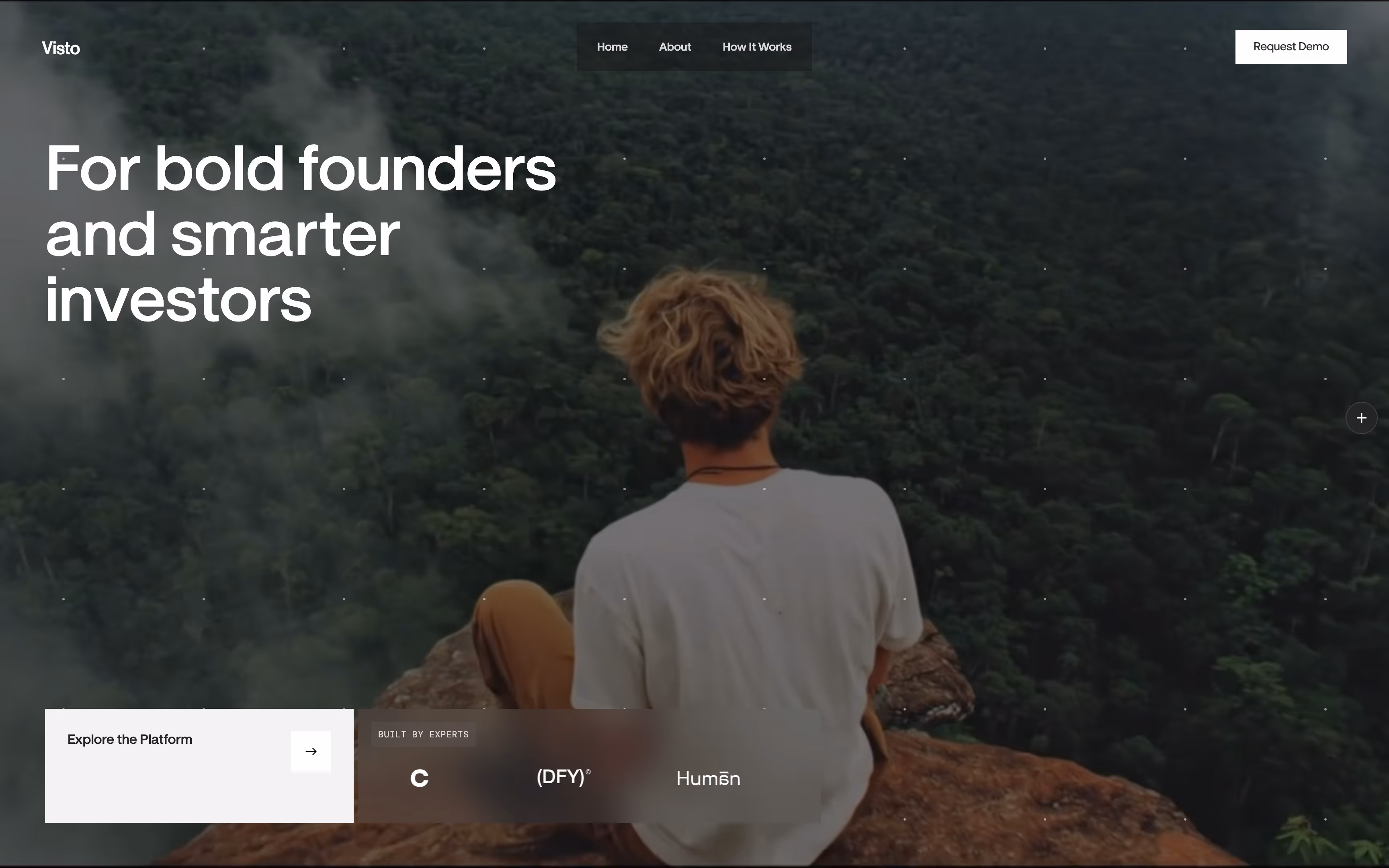 Person with blonde hair sitting on a rocky cliff overlooking a dense forest covered in fog.