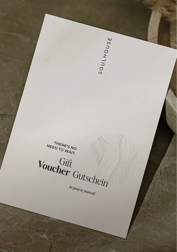 Weiße Geschenkgutschein-Karte von Soulhouse mit Schriftzügen in Englisch und Deutsch auf steinfarbenem Hintergrund.