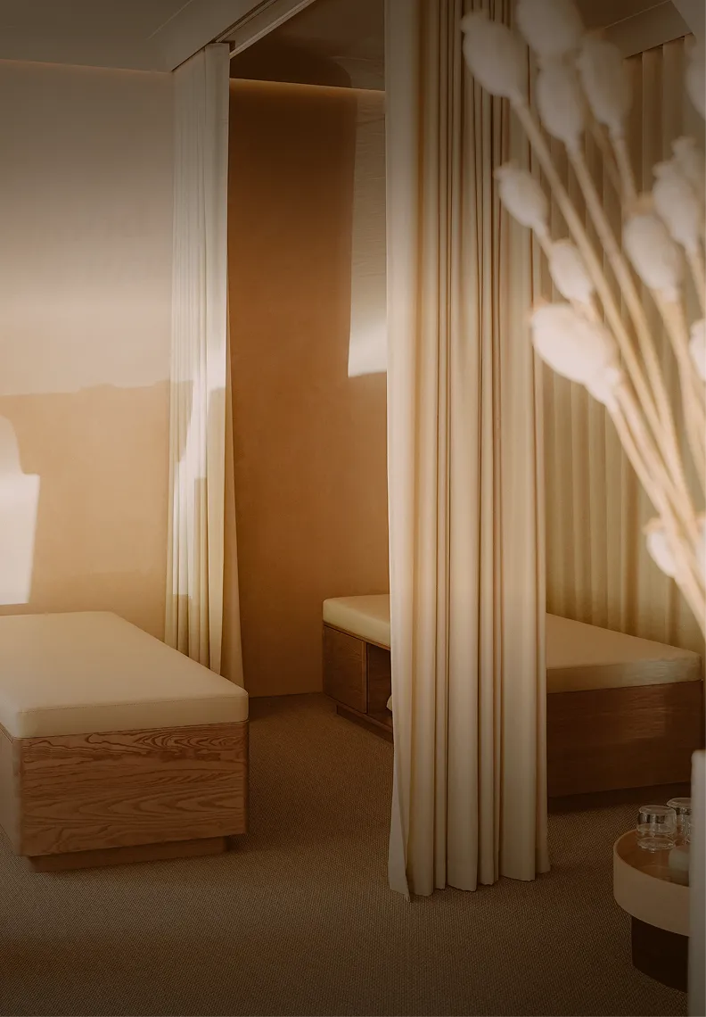 Gemütliches Soulhouse Studio mit zwei Holzbänken, beigen Polstern und Vorhängen als Raumteiler in warmem Licht.